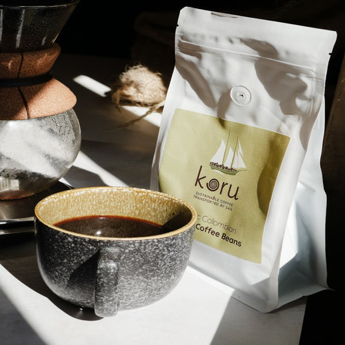 Koru coffee beans package with a cup of coffee on a wooden surface